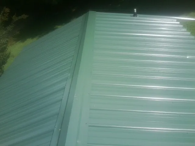 New green metal panels meeting at the ridge of a roof — Flat Roof Repair work by our crew in Orange