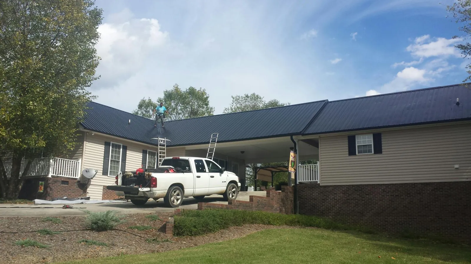 Black metal roof over a home and attached breezeway with ladders set in Orange