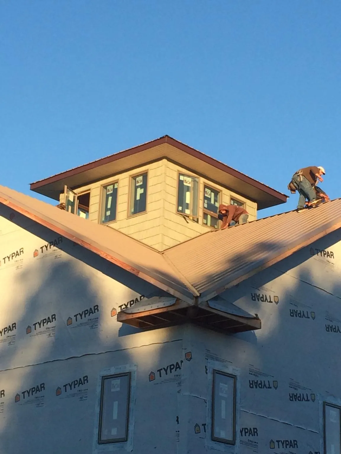 Roofers working around a rooftop cupola on a new metal roof at sunset — Roof Waterproofing in Orange by Roofing Brothers